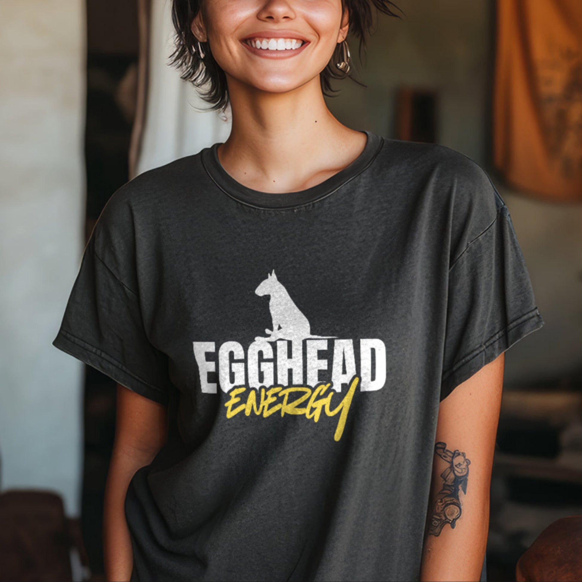 Person wearing a charcoal t-shirt with 'EGGHEAD ENERGY' text and graphic indoors.