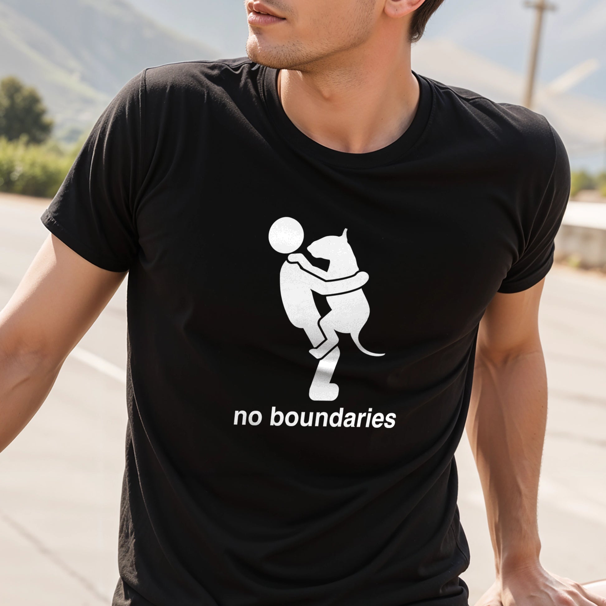 Person wearing a black t-shirt with black graphic of a dog in a persons arms and 'no boundaries' text.