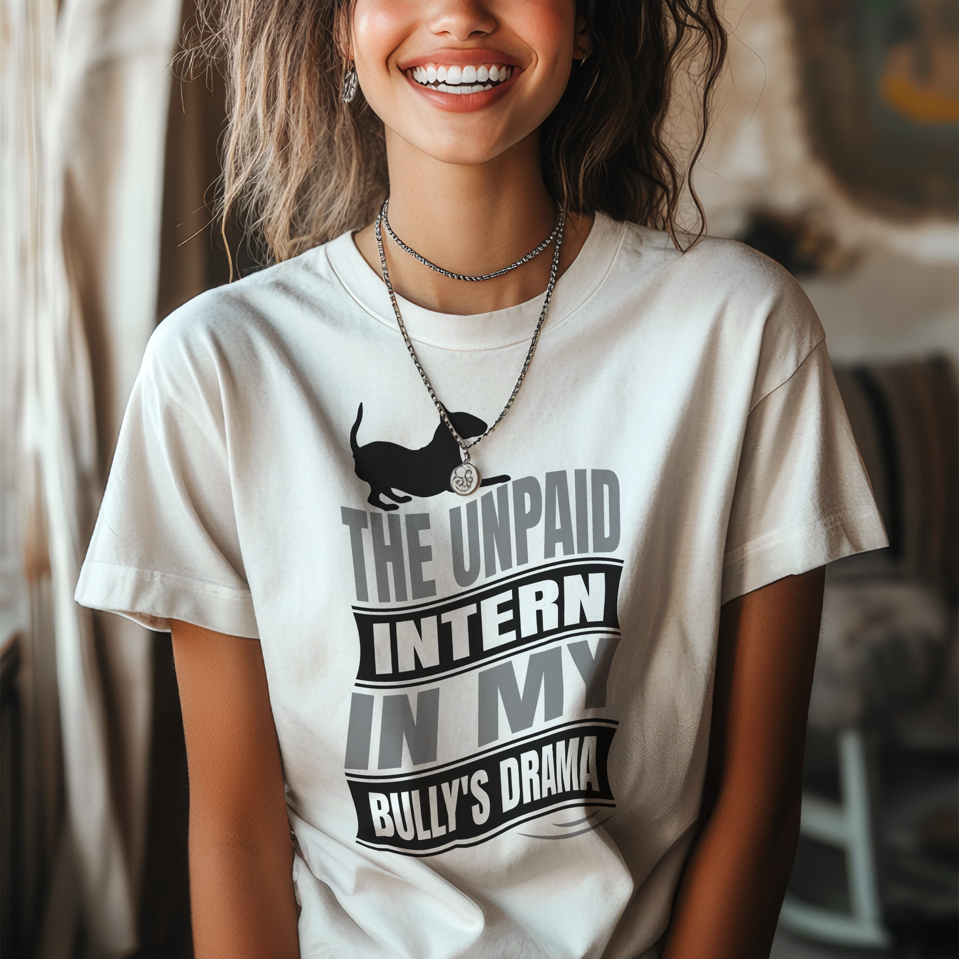 Woman wearing a white t-shirt with a graphic text reading "The unpaid intern in my bully's drama", with a graphic of a playful bull terrier. 