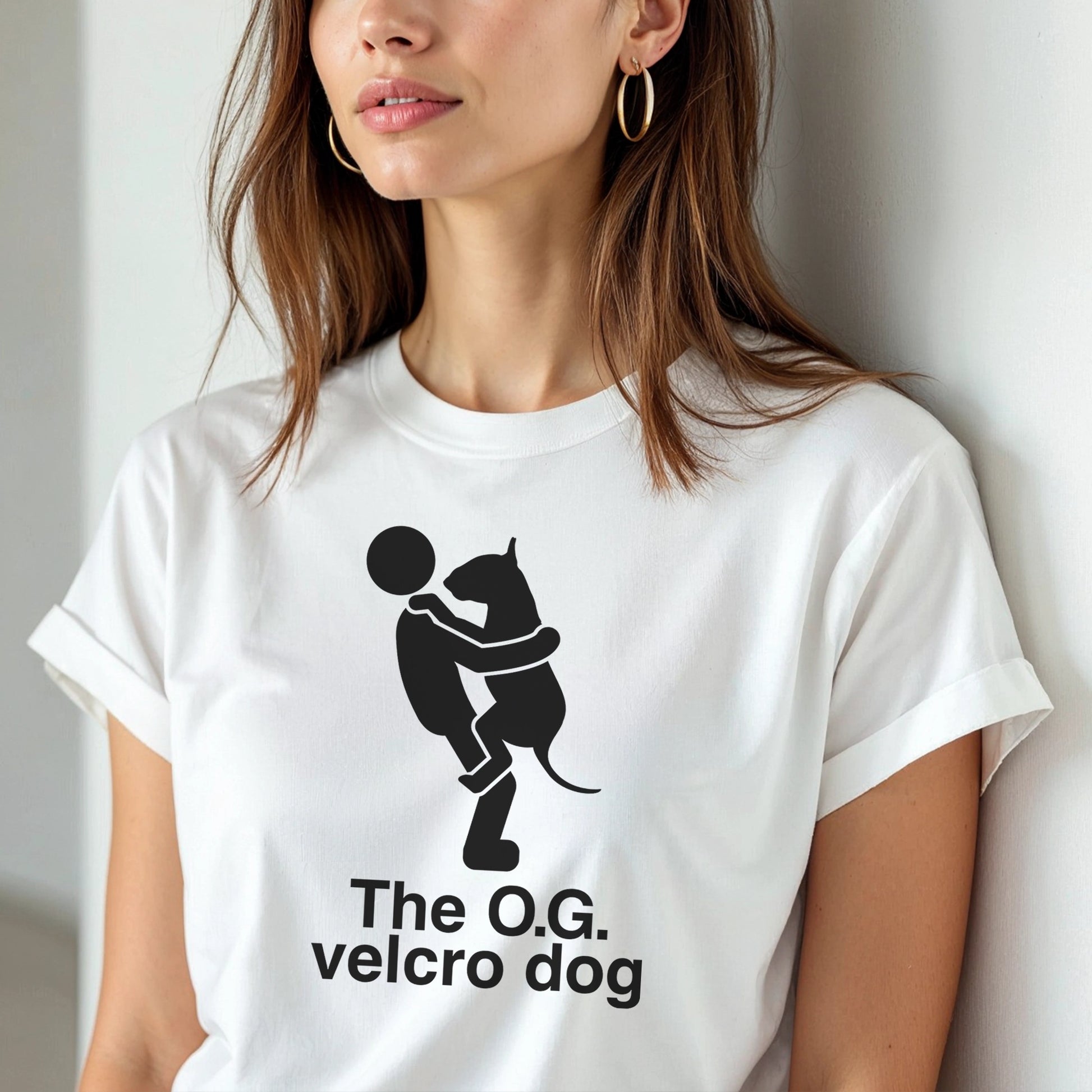Person wearing a white t-shirt with a graphic of a bull terrier jumping into a persons arms, and text 'The O.G. velcro dog'.